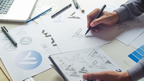 Designer sketching logo concepts on paper for brand identity design